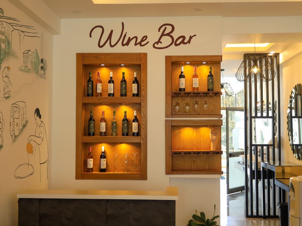 Gursha Kitchen Wine Bar — Warm lit wooden shelves with wine collection